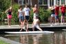 Surfplank varen en koekhappen ineen. 2 personen per surfplank, met de hanen peddelend een afstand van ± 20 meter afleggen naar de brug. Dam om de beurt koekhappen en weer terug naar het startpunt. Een en ander werd per straat uitgevoerd in estafette vorm.