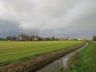 Donkere wolken boven Goënga met regenboog voorafgaande aan een naderende regenbui.