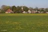 Gezicht op her dorp Goënga op toen nog Koninginnedag. In de weilanden bloeiden nog bloemen, nu staar er gifgroen raaigras zonder een bloem op deze landerijen.