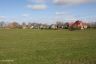 Voorjaar. Nog even en de bomen worden groen, het gras wordt weer gemaaid en de vogels keren terug in het land. Rechts op de voorgrond een stukje dorpsuitbreiding door middel va 2 woningen. Daar achter, niet zichtbaar een uitbreiding met 9 woningen, genaamd 'De Boppeslag'.