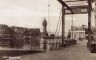 Rechts de in 1901 geplaatste 'Wonderbrug' waarvan de naam nog steeds een raadsel is. De brug bracht je naar de Geeuwkade en de in 1930 daar gestichte veemarkt. Kijkend door de brug
de kaaspakhuizen van Halbertsma, met links fier de watertoren uit 1909-1910.