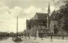 Het is 1920 als de fotograaf deze foto maakt van de Katholieke kerk aan de Harinxmakade. Links op de foto zijn nog een paar huizen van de Prinsengracht te zien.
