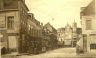 Gezicht op de Wijde Burgstraat met links de winkel in Reistassen, koffers enzv. Rechts op de hoek de latere tabakswinkel / fabriek van Zandhuizen. Op de achtergrond het pand van kledingwinkel Bervoets. Slogan: Voor iets goeds, naar Bervoets. 