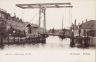 Centraal de brug over de Woudvaart, die vroeger Steenwijker vaart heette. Rechts de in 1887 aangelegde Selfhelp straten, naar Amerikaans voorbeeld en afgeleid van ( Help your self ).
Links de Wouvaartkade met geheel links het kruidenierswinkeltje van De Vries en dochter Klaske.