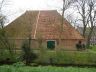 De zijkant van de boerderij, waarvan de dakpannen reeds zijn verwijderd. Rechts op de foto het eerder gerestaureerde voorhuis van de Kop- hals- romp boerderij.