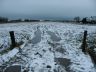 Onheilspellende sneeuwlucht, met reflectie in ruiten van een boerderij bij ondergaande zon.