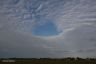 Gat in een toenemend wolkendek boven het dorp Goënga.